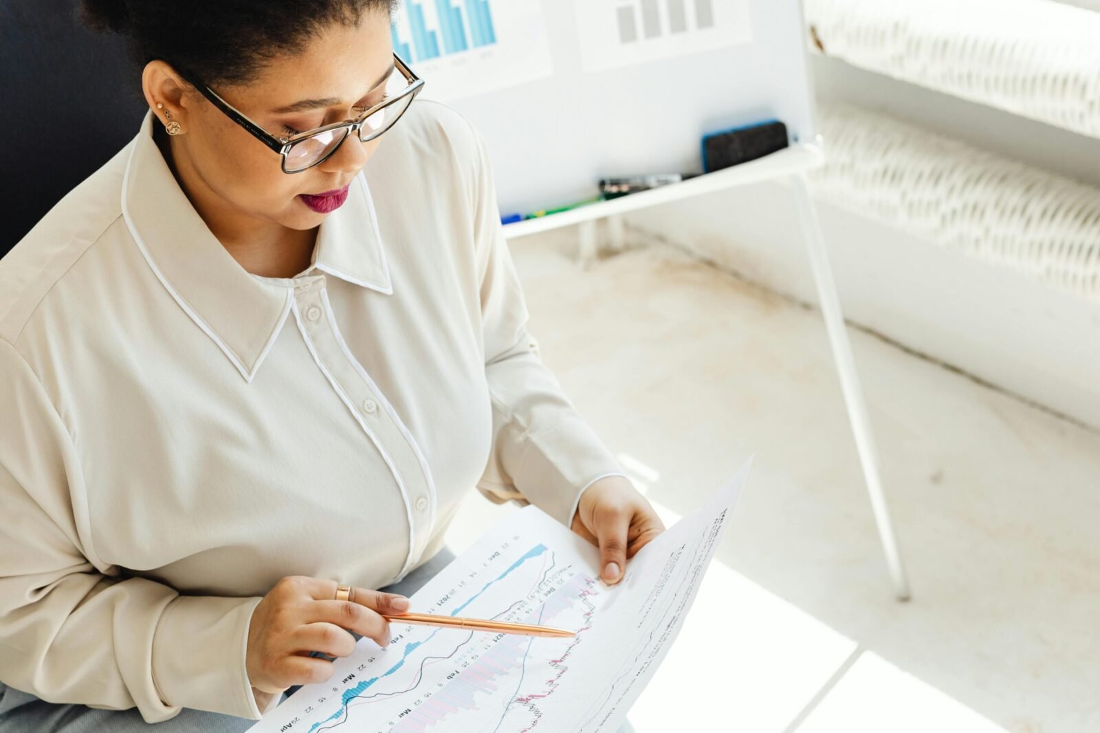 African American woman analyzing financial charts indoors with focus on market trends.